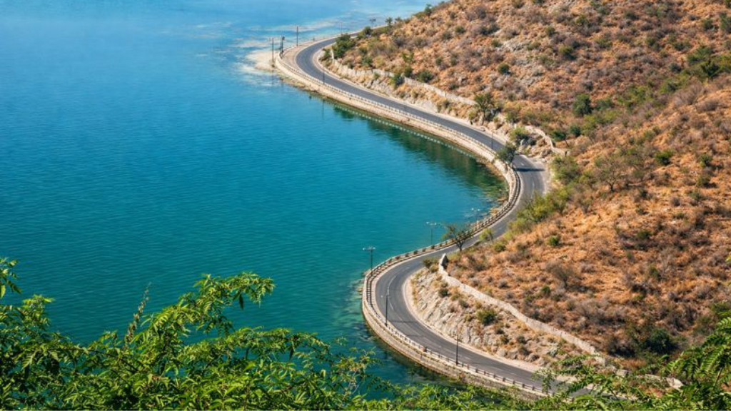 Scenic aerial view of Rani Road, Udaipur, curving along the Fateh Sagar lake—one of the city’s most picturesque spots for pre-wedding photoshoots.
